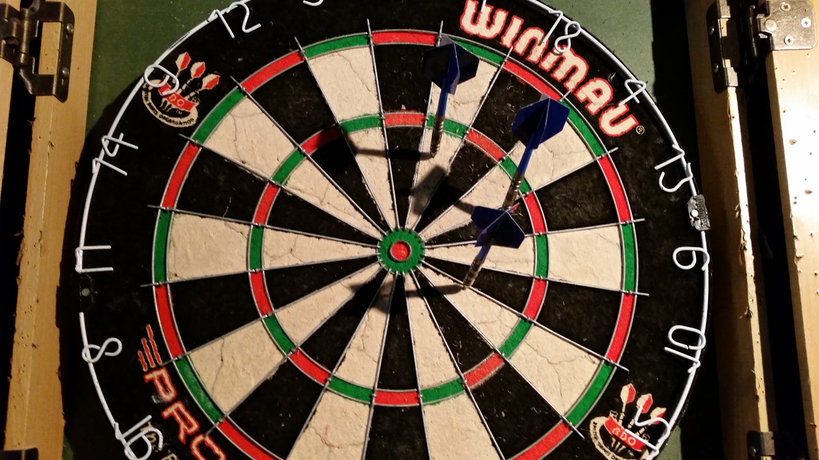 Bristle dartskive med tre pile i, hvor double- og triplering samt bullseye er tydelige